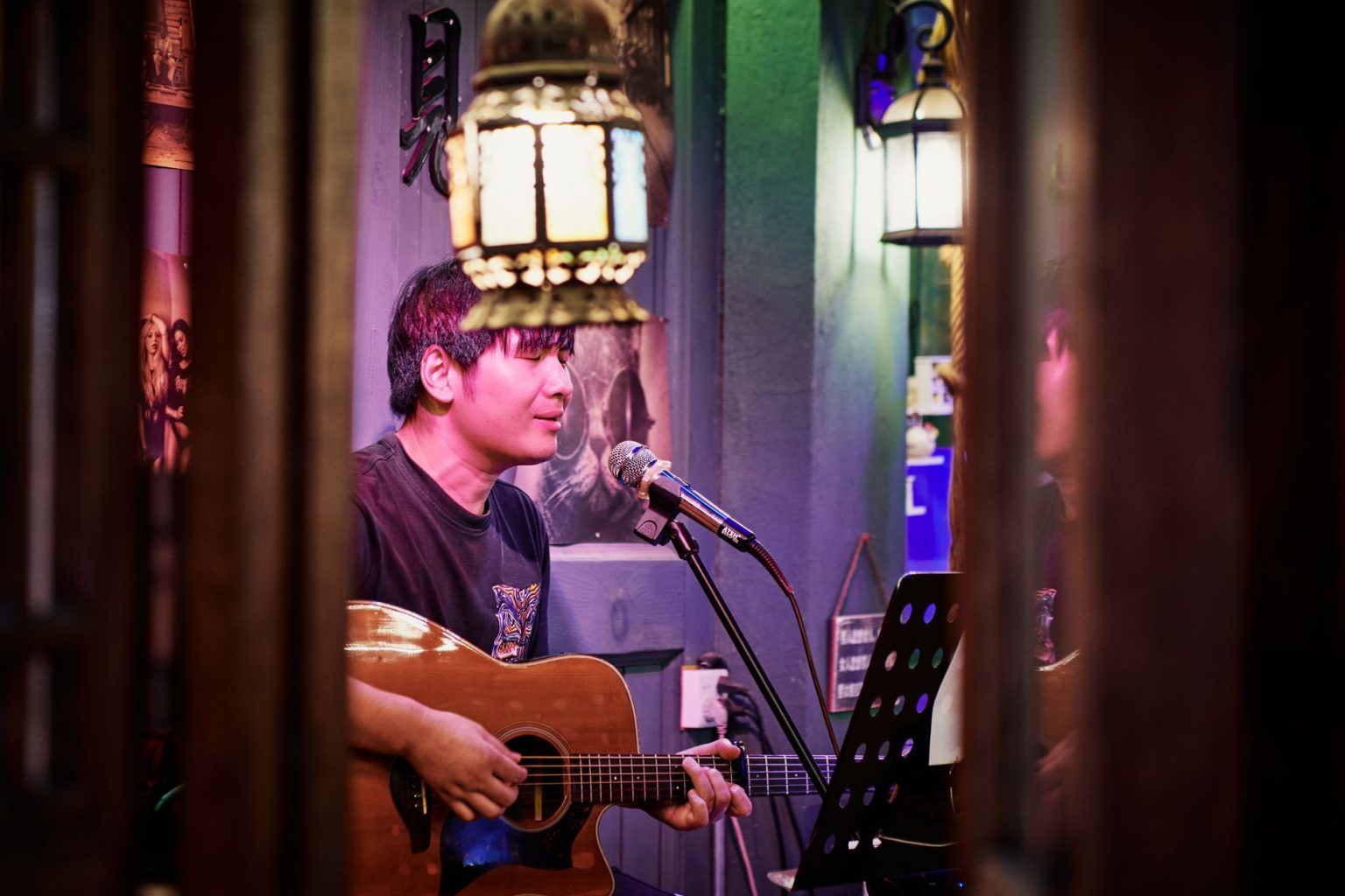 Músico canta e toca violão em uma apresentação musical em ambiente interno.