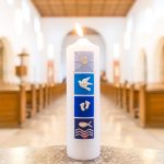 Fonte batismal com vela acesa no interior de uma igreja, em referência a uma cerimônia cristã de batismo