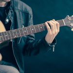 Guitarrista toca violão durante uma apresentação musical.
